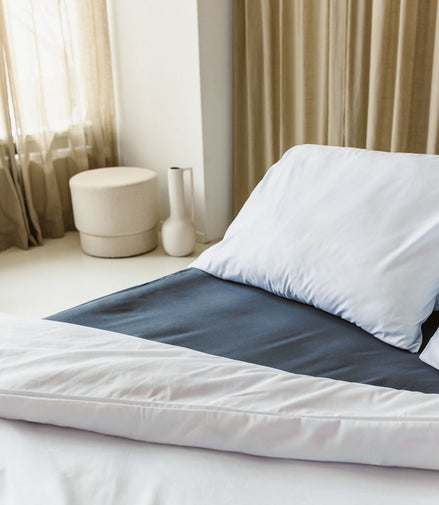 Opgemaakt bed met wit kussensloop en wit dekbedovertrek